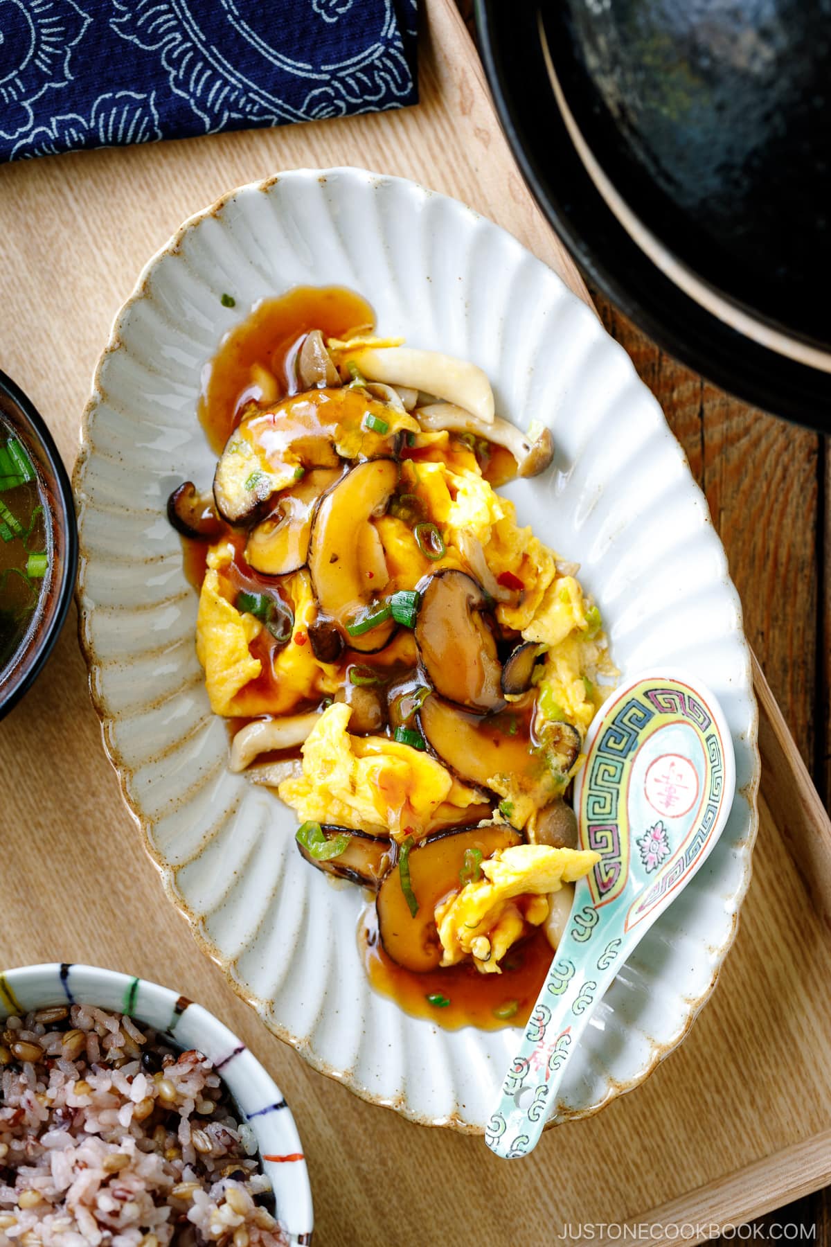 A fluted oval shape containing stir-fried mushrooms and eggs drizzled with ankake sauce.