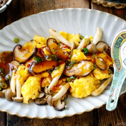 A fluted oval shape containing stir-fried mushrooms and eggs drizzled with ankake sauce.