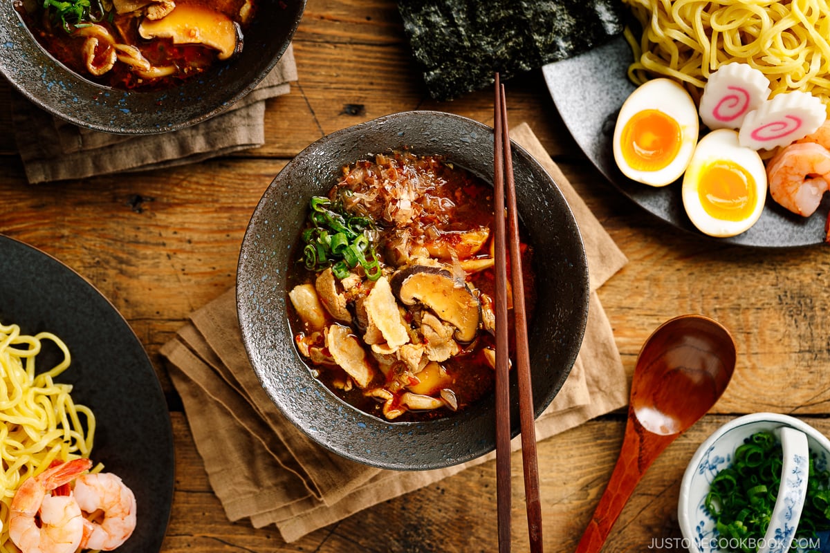 Bowls of Tsukemen dipping soup broth and a plate of ramen noodles and toppings.