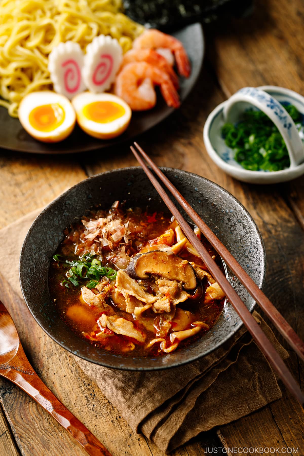 Bowls of Tsukemen dipping soup broth and a plate of ramen noodles and toppings.