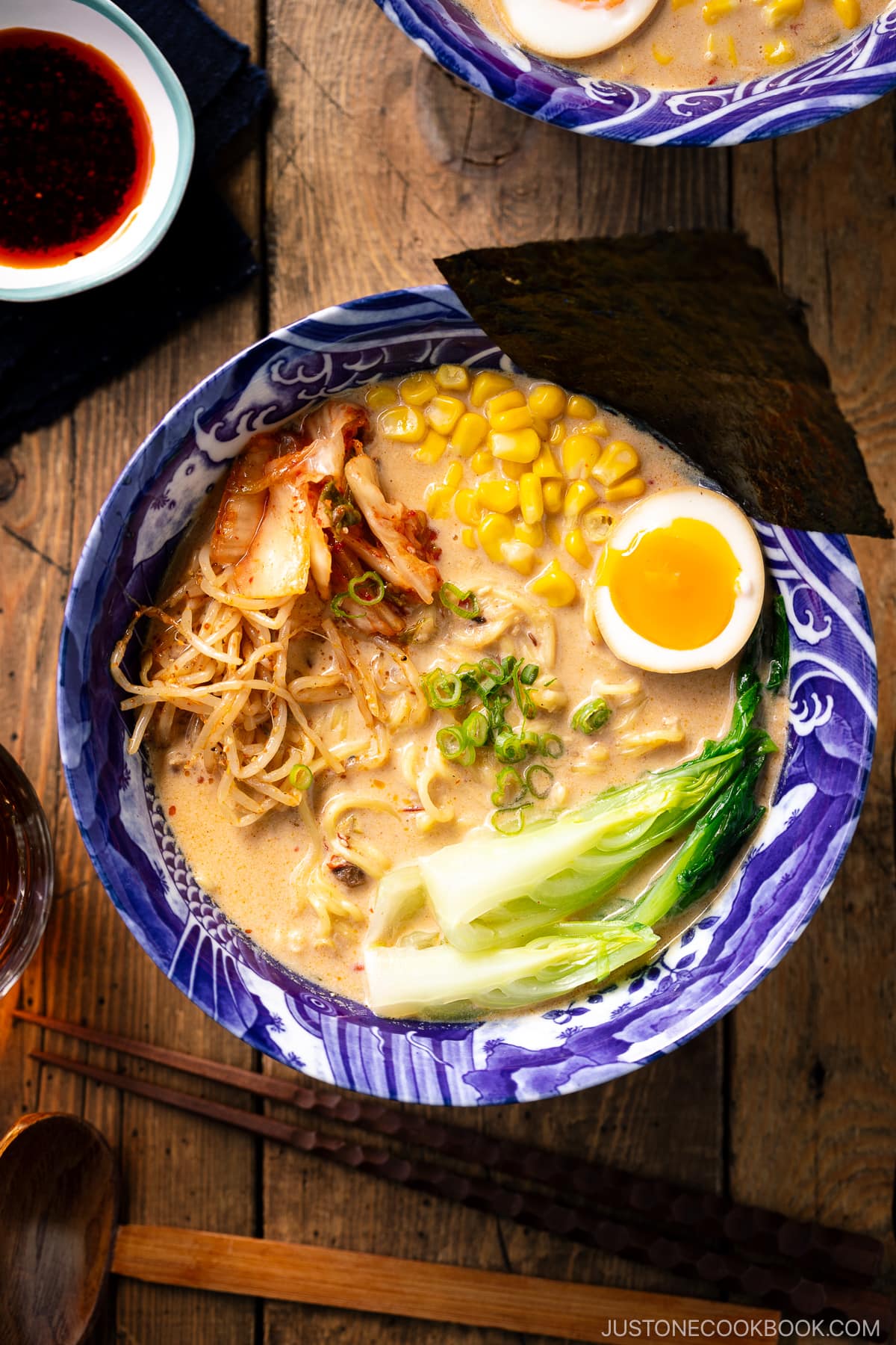 A bowl of Vegetarian Ramen topped with ajitama (soy marinated egg), spicy bean sprouts, corn, and a green veggie.