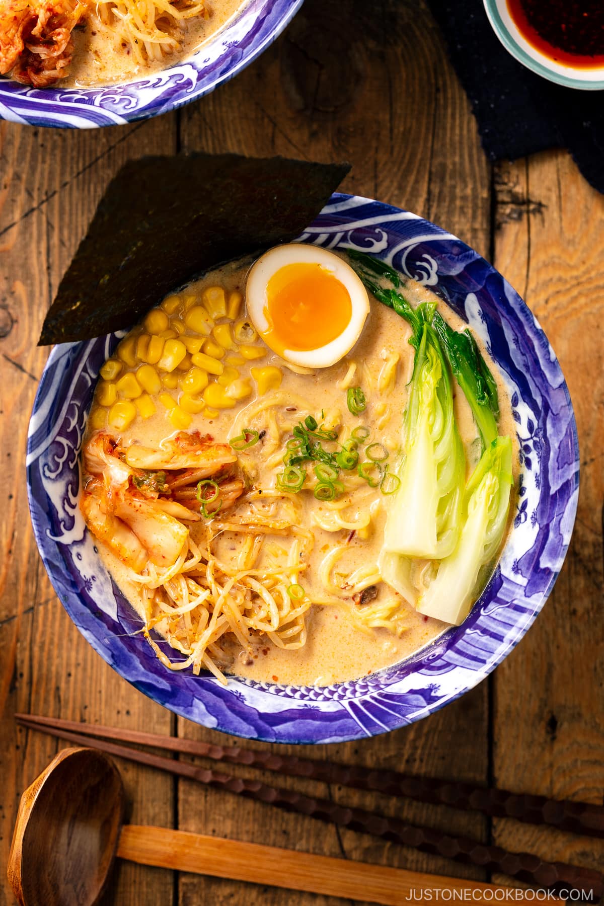 A bowl of Vegetarian Ramen topped with ajitama (soy marinated egg), spicy bean sprouts, corn, and a green veggie.