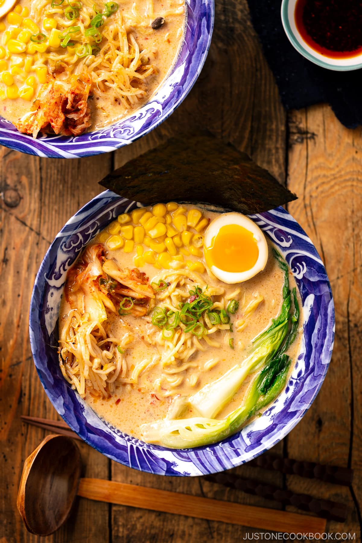 A bowl of Vegetarian Ramen topped with ajitama (soy marinated egg), spicy bean sprouts, corn, and a green veggie.