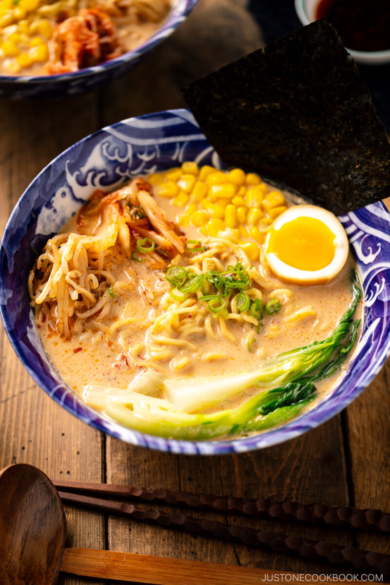 A bowl of Vegetarian Ramen topped with ajitama (soy marinated egg), spicy bean sprouts, corn, and a green veggie.