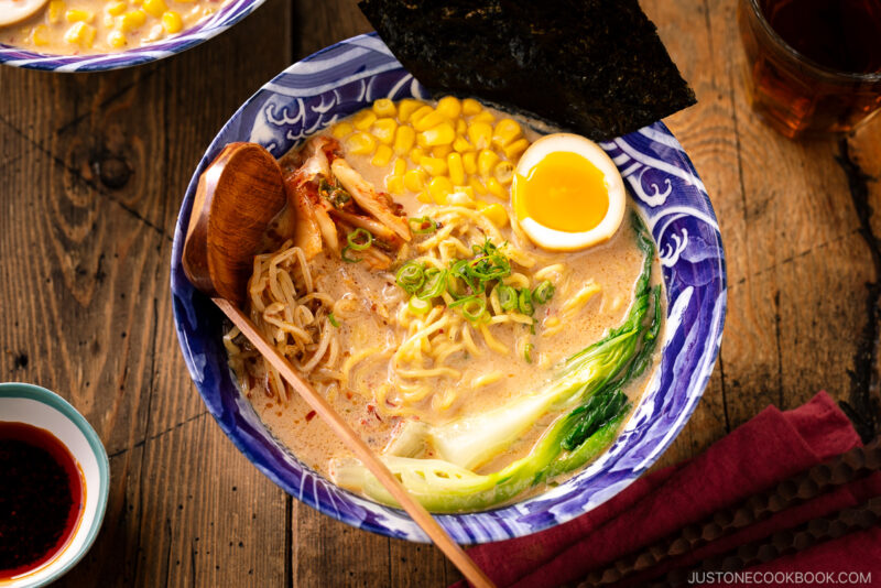 A bowl of Vegetarian Ramen topped with ajitama (soy marinated egg), spicy bean sprouts, corn, and a green veggie.