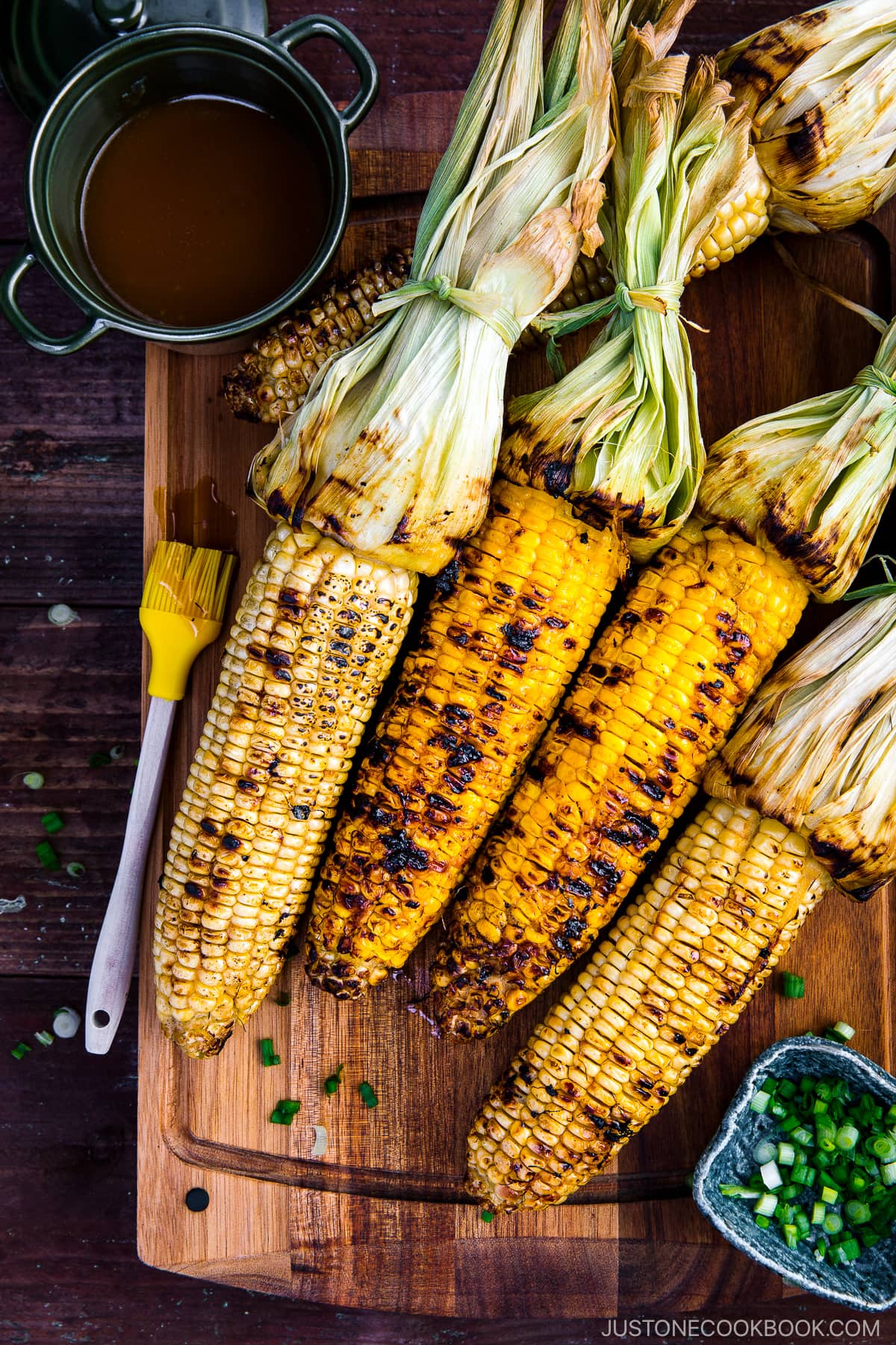 Grilled corn on the wooden cutting board.