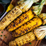 Grilled corn on the wooden cutting board.