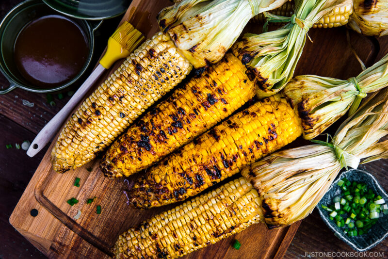 Grilled corn on the wooden cutting board.