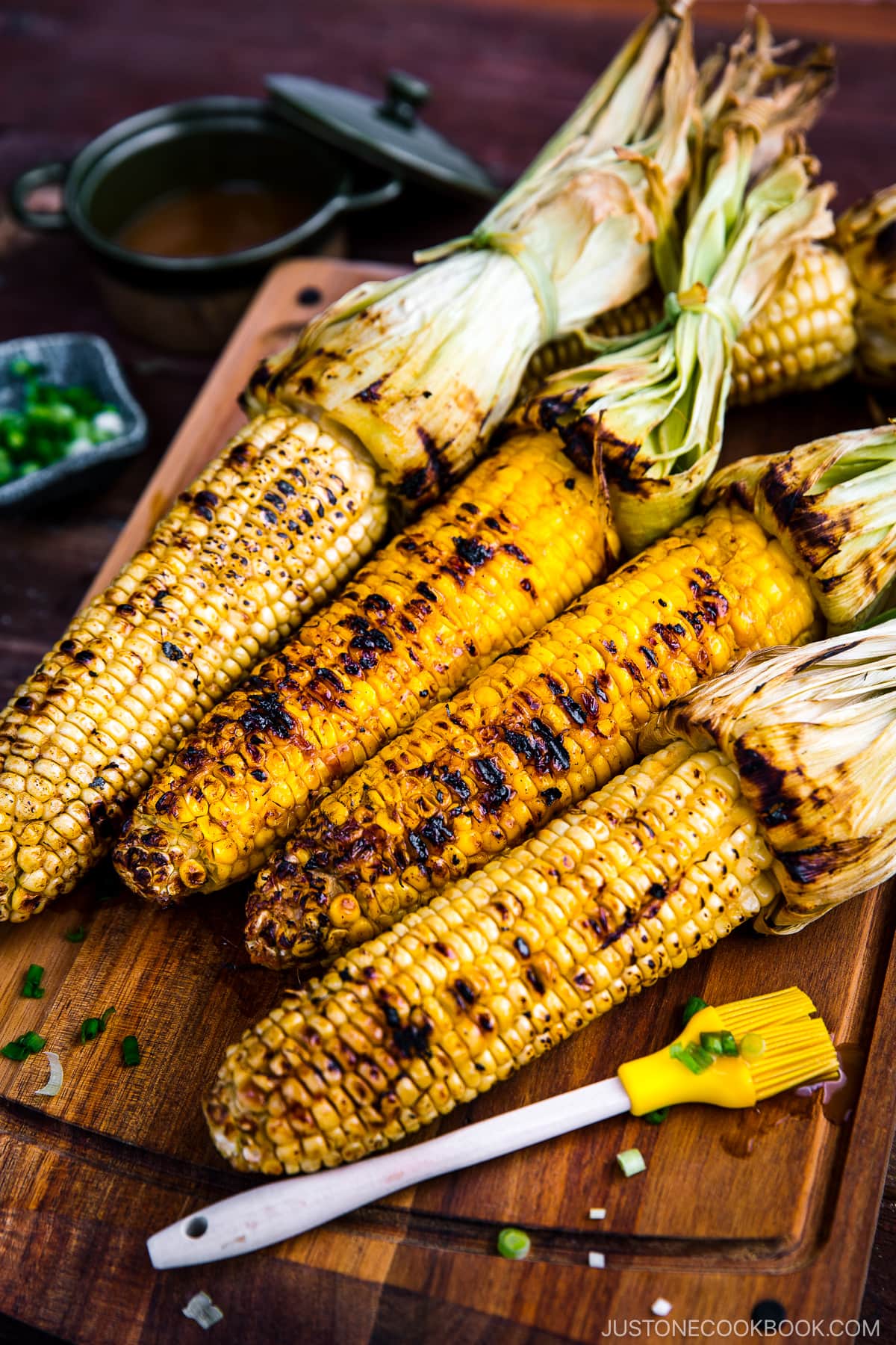 Grilled corn on the wooden cutting board.