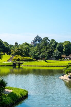 a castle and a garden behind a pond