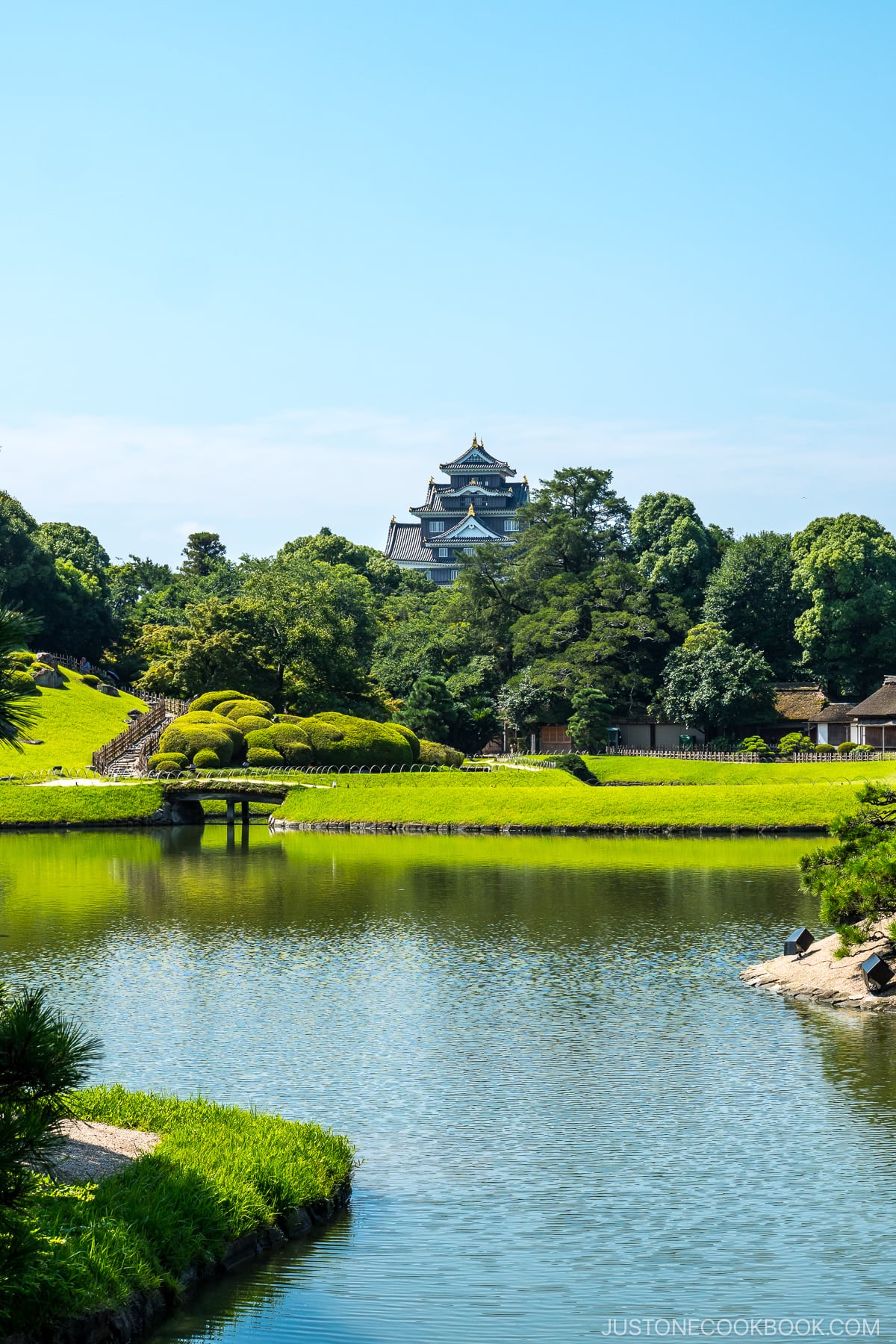 a castle and a garden behind a pond