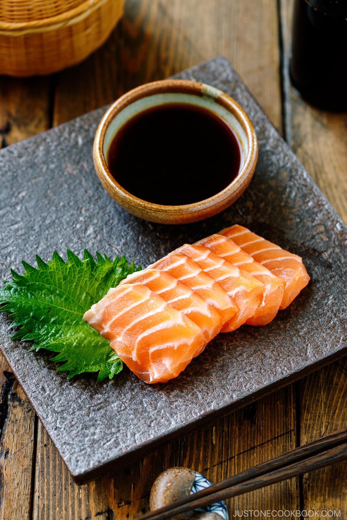 Salmon sashimi on the platter with smoked soy sauce in a small plate.