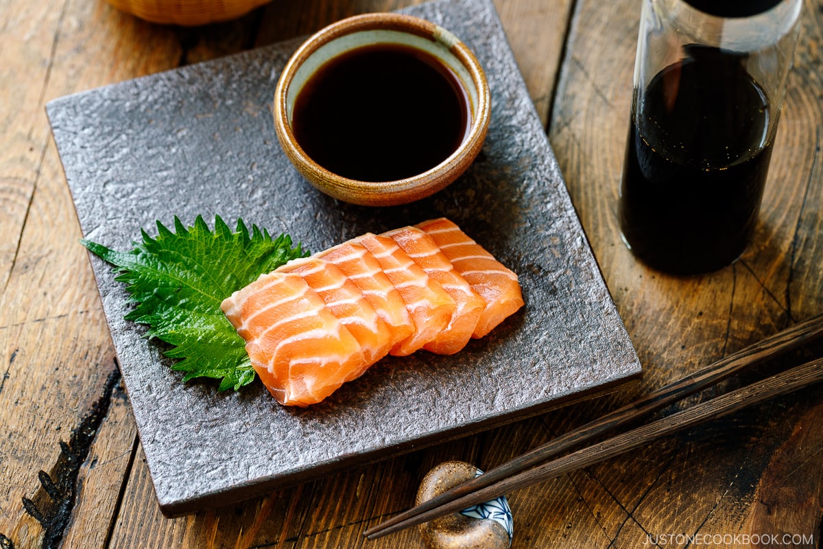 Salmon sashimi on the platter with smoked soy sauce in a small plate.