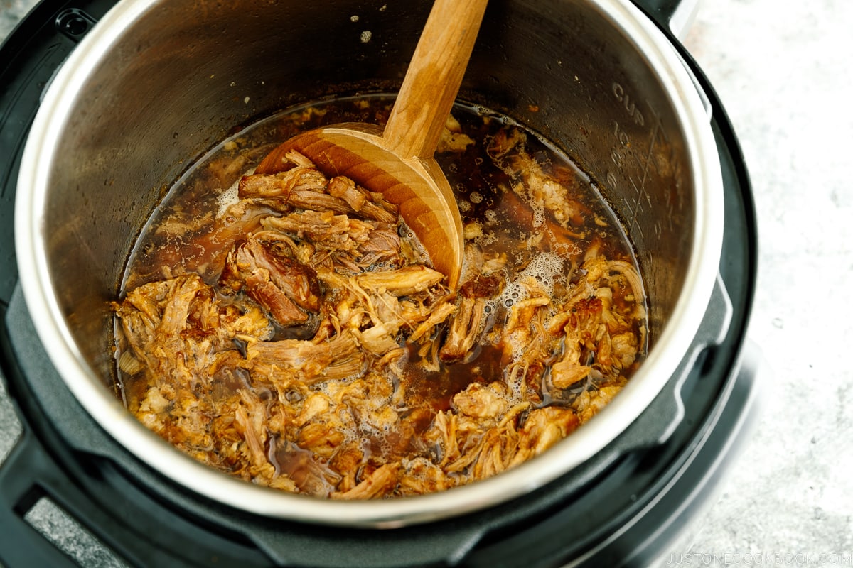 The Instant Pot containing juicy and fall-apart tender pulled pork.