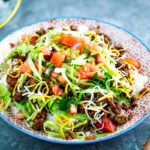 Colorful plates containing Okinawa Taco Rice with flavorful taco fixings served on a bed of hot Japanese white rice.