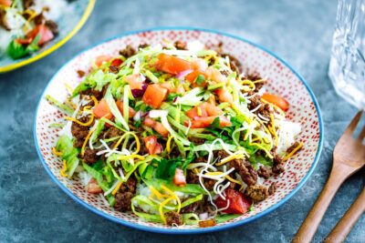 Colorful plates containing Okinawa Taco Rice with flavorful taco fixings served on a bed of hot Japanese white rice.