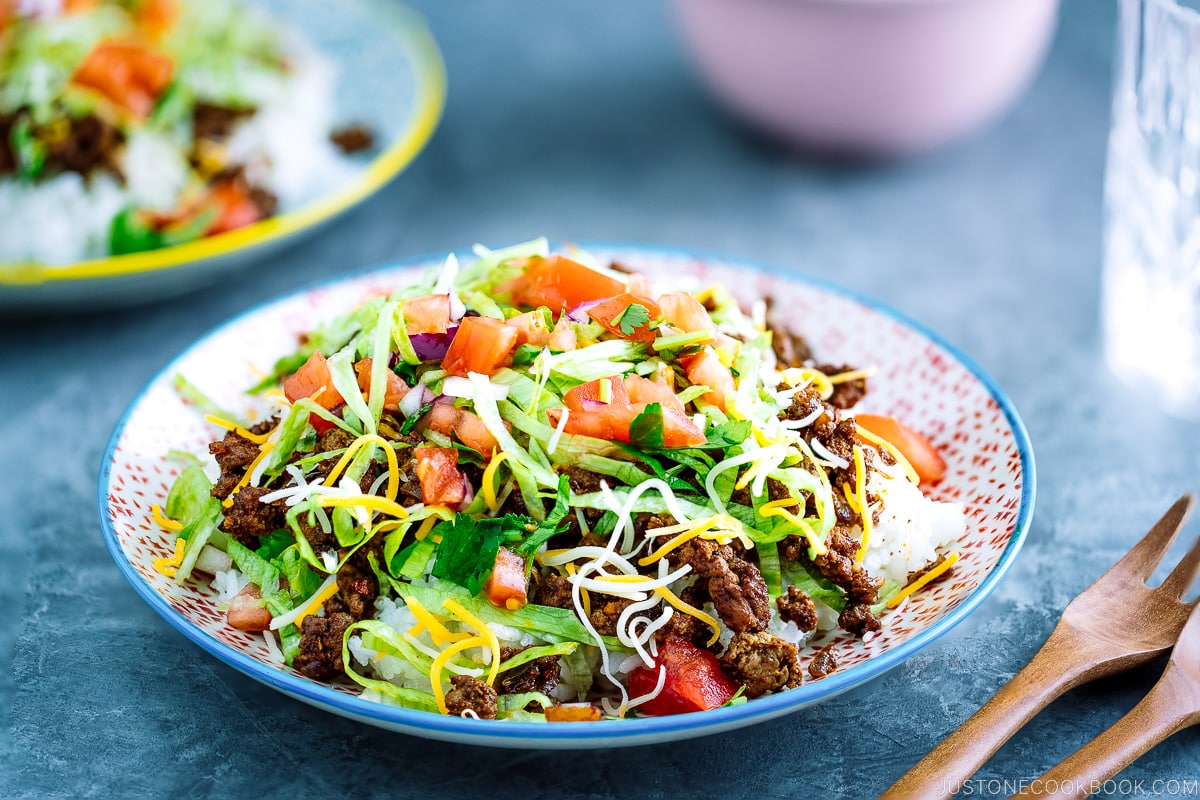Colorful plates containing Okinawa Taco Rice with flavorful taco fixings served on a bed of hot Japanese white rice.