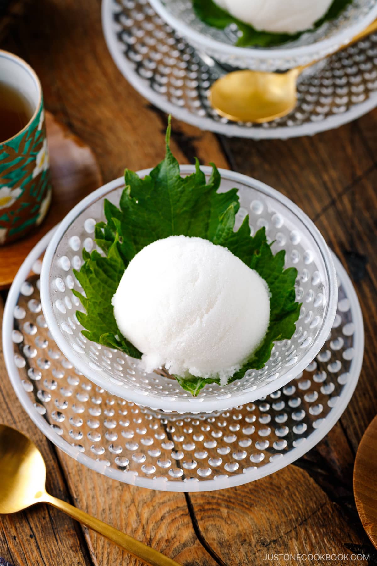 A white glass bowl containing Shiso Sorbet garnished with shiso leaf.