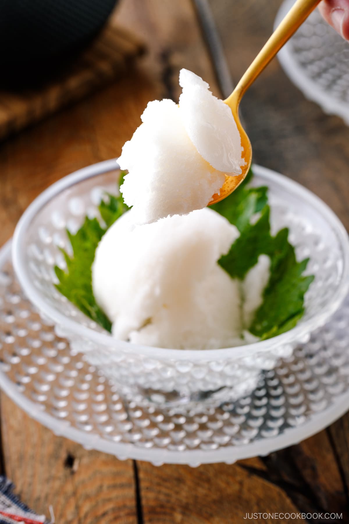 A white glass bowl containing Shiso Sorbet garnished with shiso leaf.