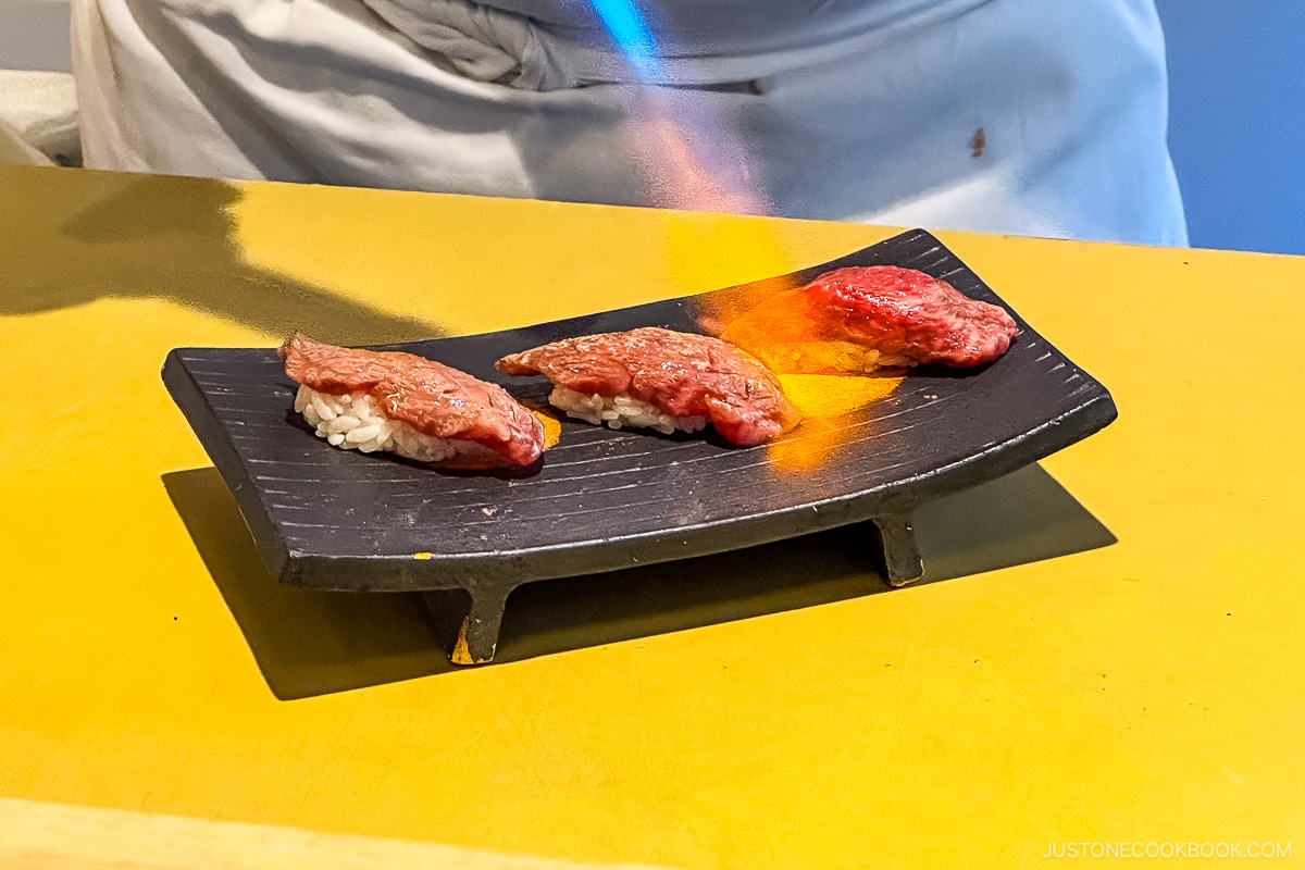 sushi being seared on a black plate