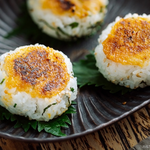 Miso Yaki Onigiri placed on a bizenware ceramic plate garnished with shiso leaf.