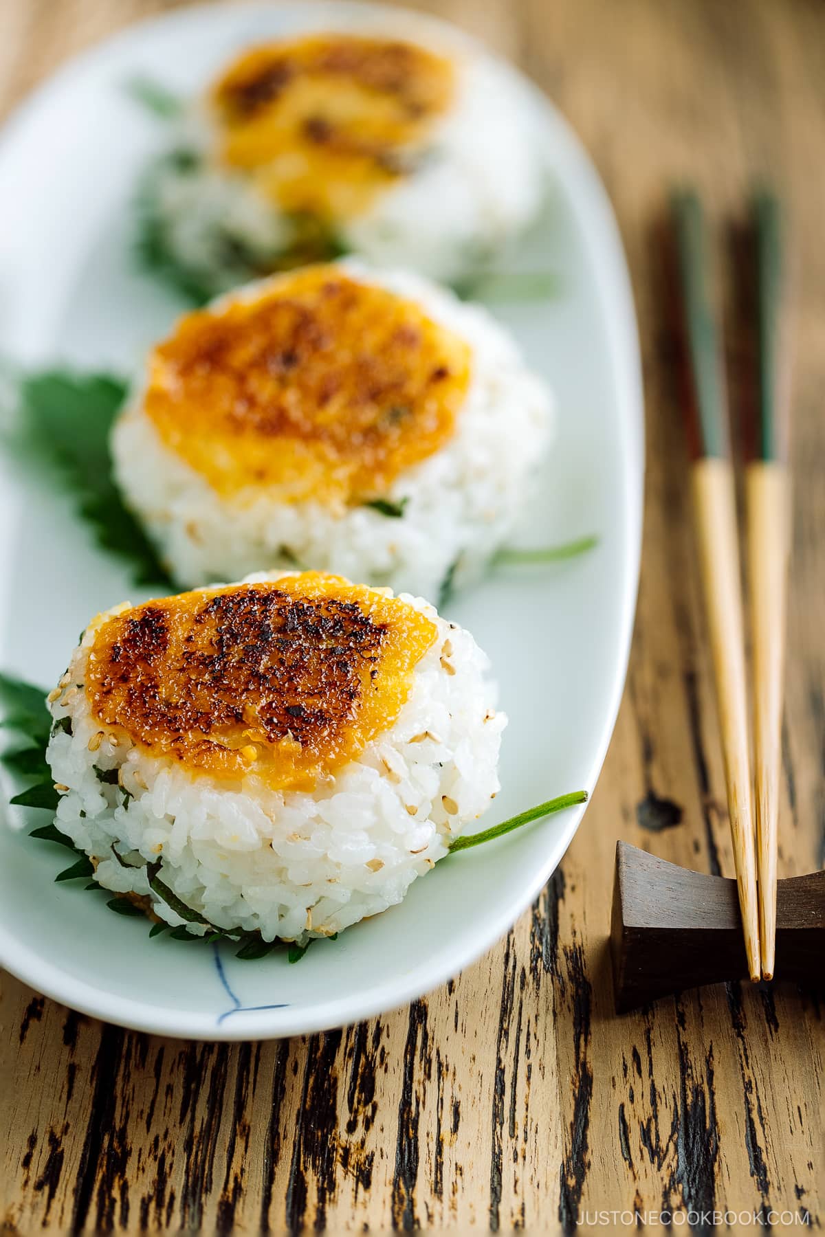 Miso Yaki Onigiri placed on a bizenware ceramic plate garnished with shiso leaf.