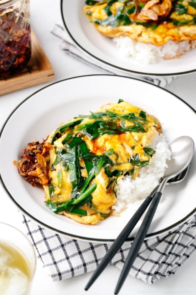 A white plate containing Stir-Fried Garlic Chives and Egg Over Rice.