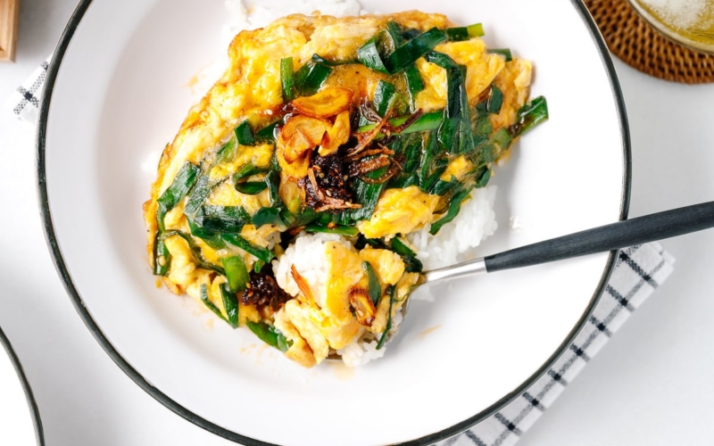 A white plate containing Stir-Fried Garlic Chives and Egg Over Rice.