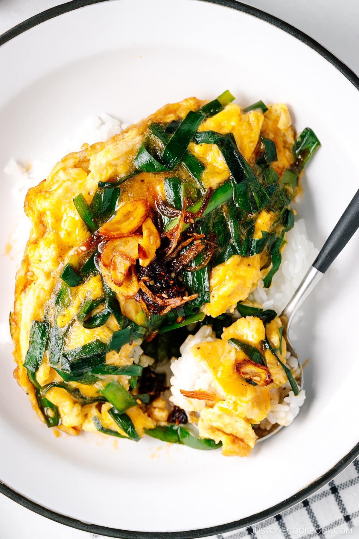 A white plate containing Stir-Fried Garlic Chives and Egg Over Rice.