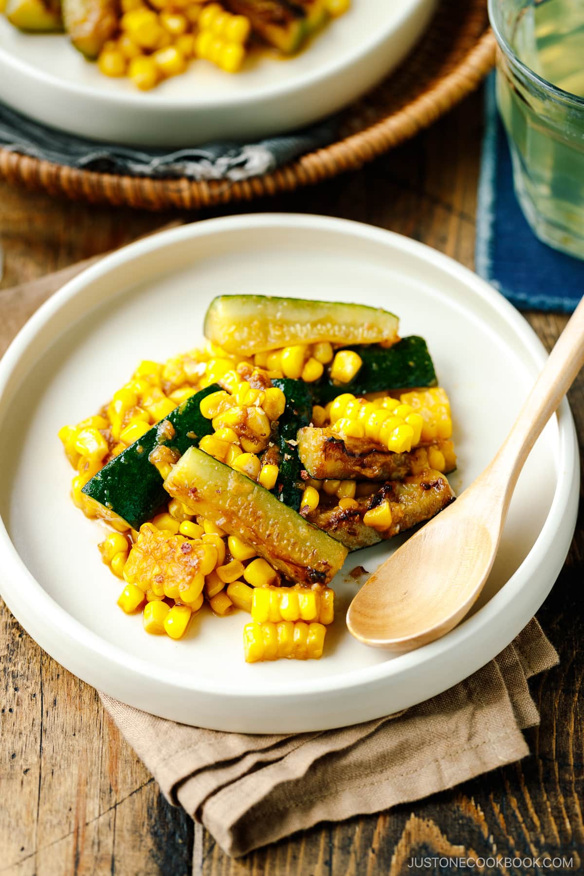 A white plate containing zucchini corn stir fry seasoned with miso butter.