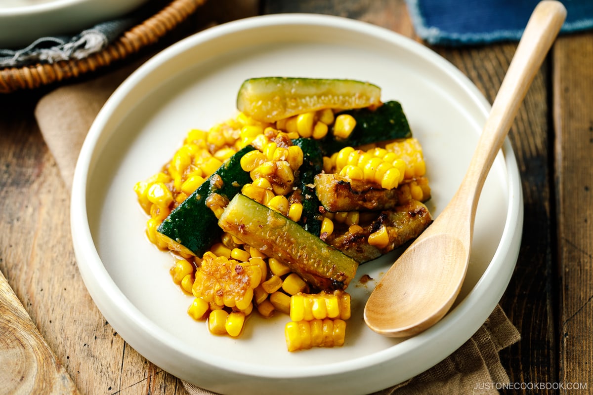 A white plate containing zucchini corn stir fry seasoned with miso butter.