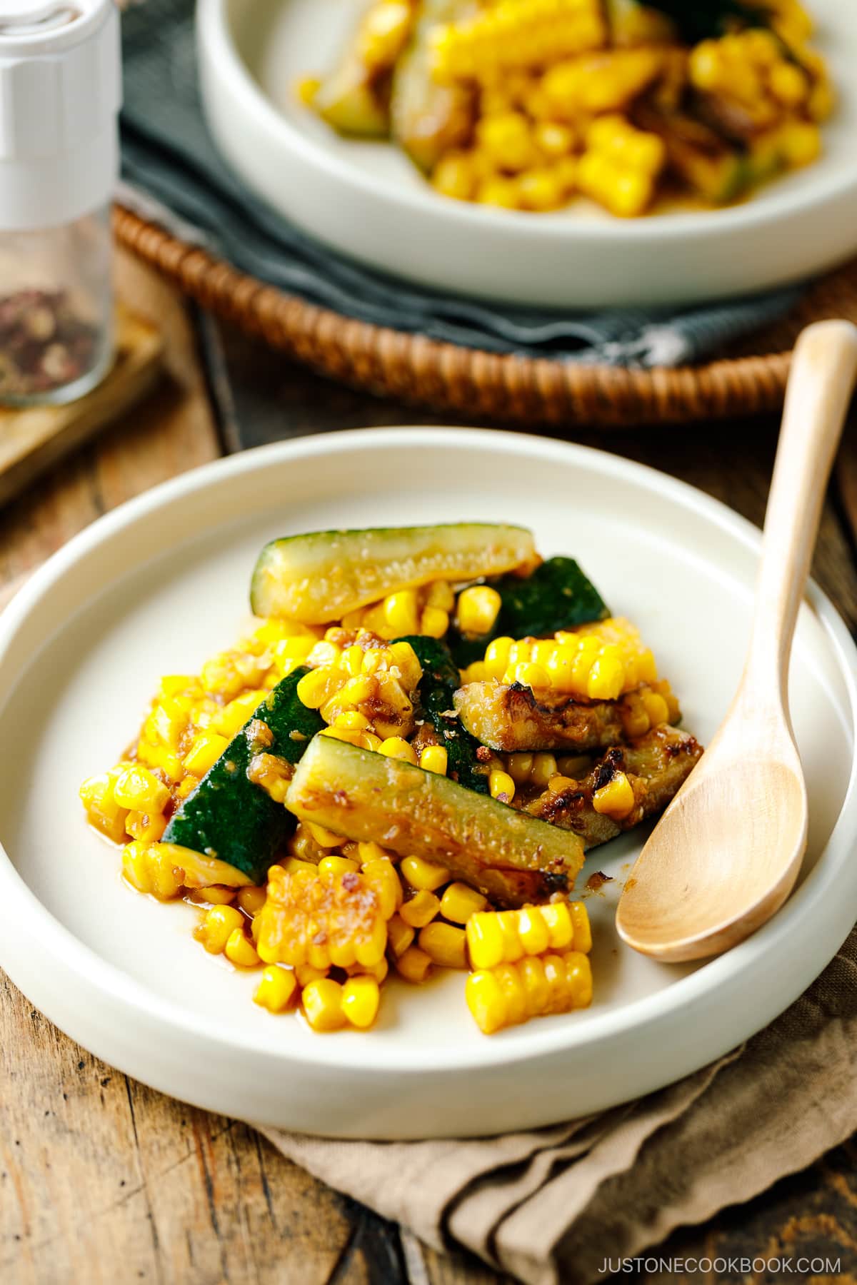 A white plate containing zucchini corn stir fry seasoned with miso butter.
