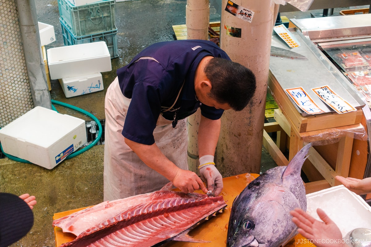 Scraping carcass of tuna to serve to customers at local market