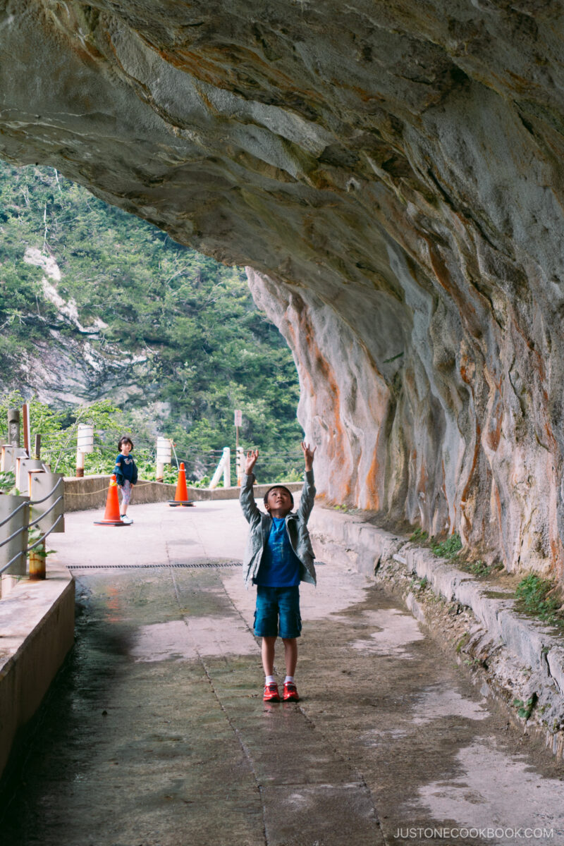 a boy standing under Hitokui-iwa