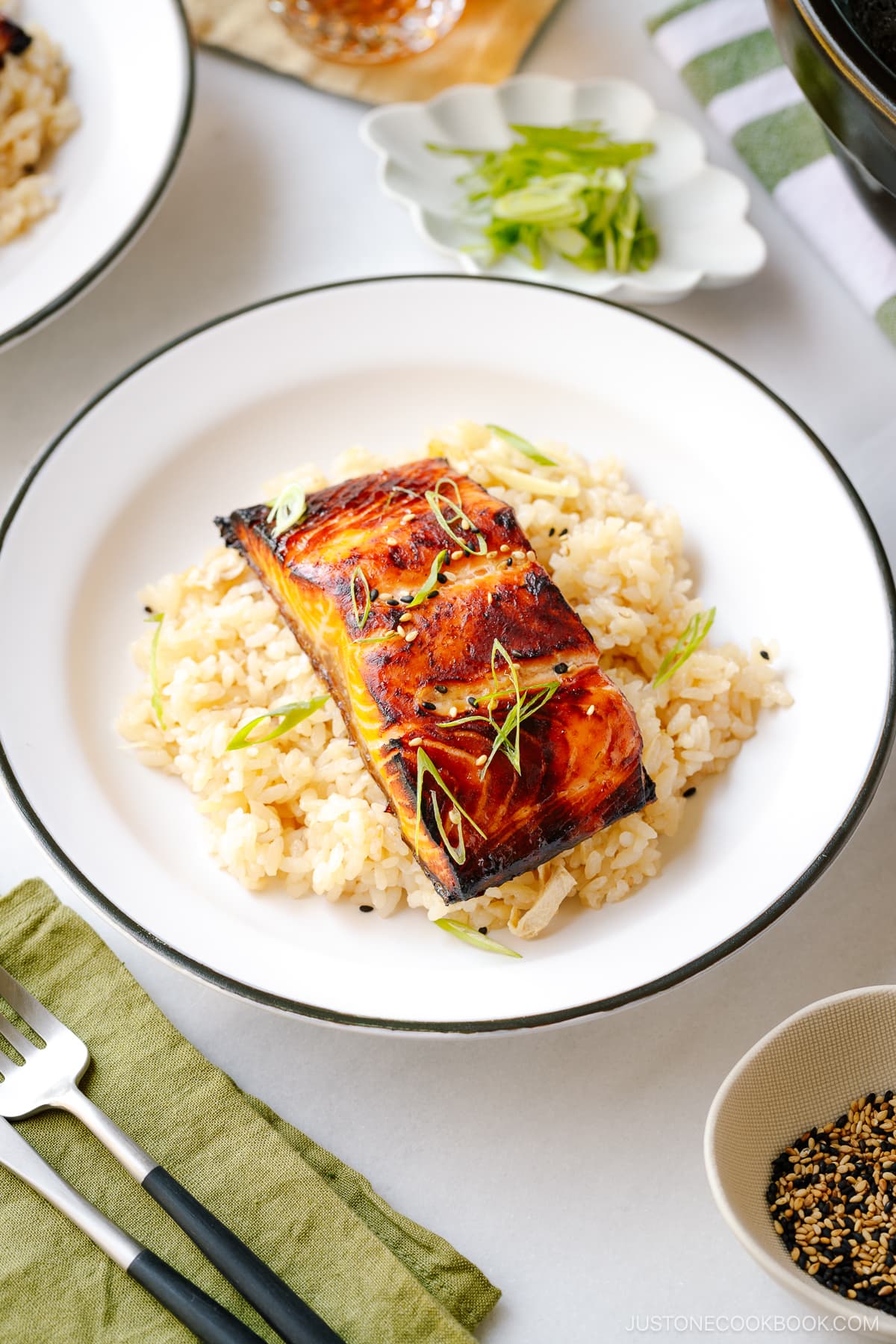 A white plate containing Broiled Miso Salmon served over ginger rice.