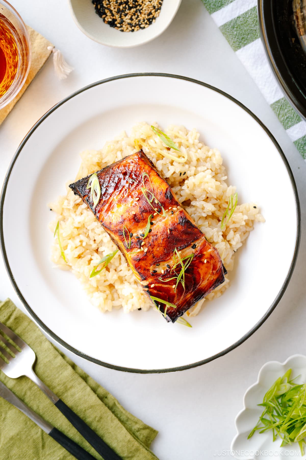 A white plate containing Broiled Miso Salmon served over ginger rice.