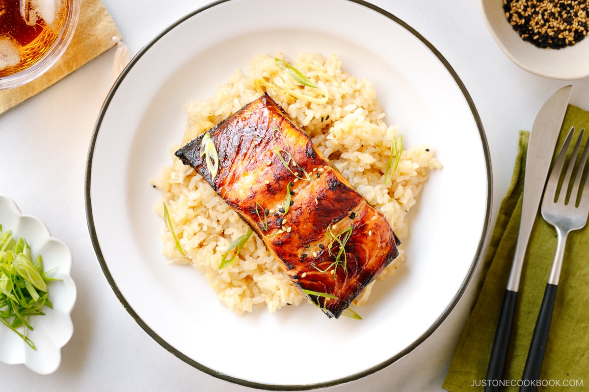 A white plate containing Broiled Miso Salmon served over ginger rice.