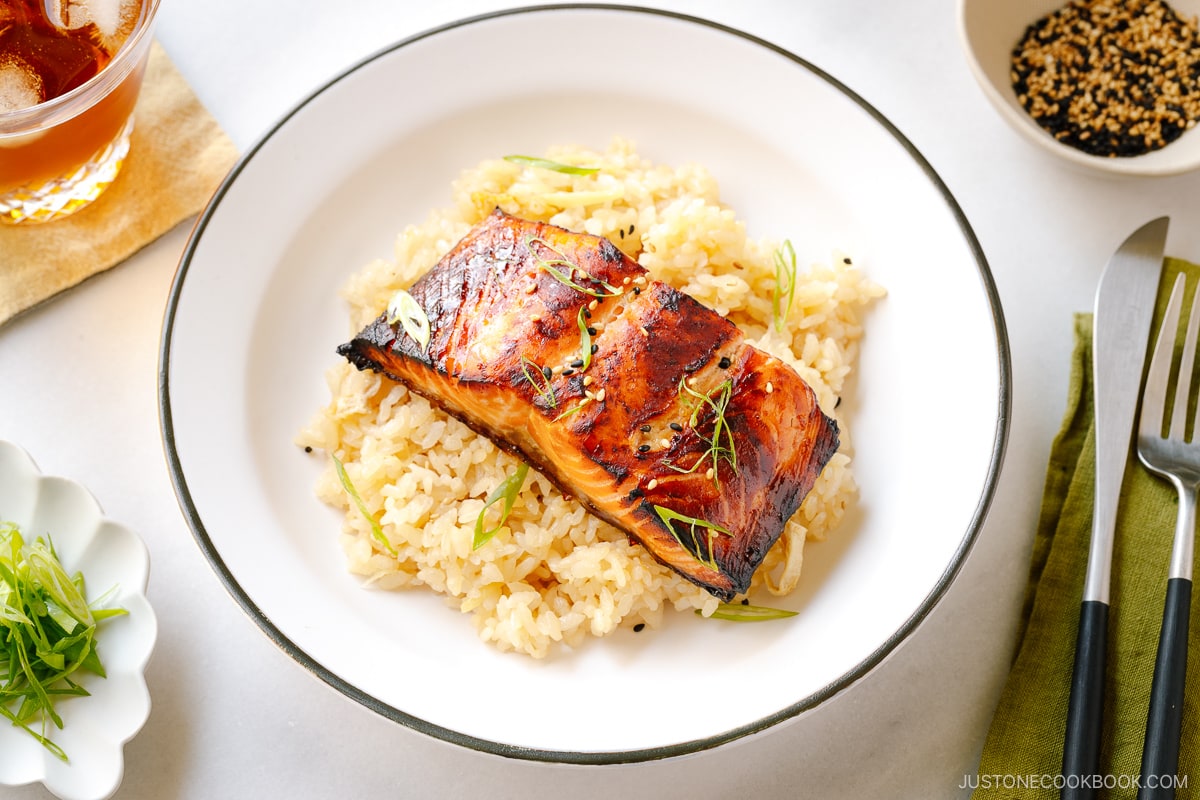 White plates containing Broiled Miso Salmon served over ginger rice.