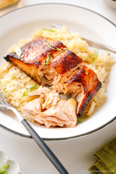 A white plate containing Broiled Miso Salmon served over ginger rice.