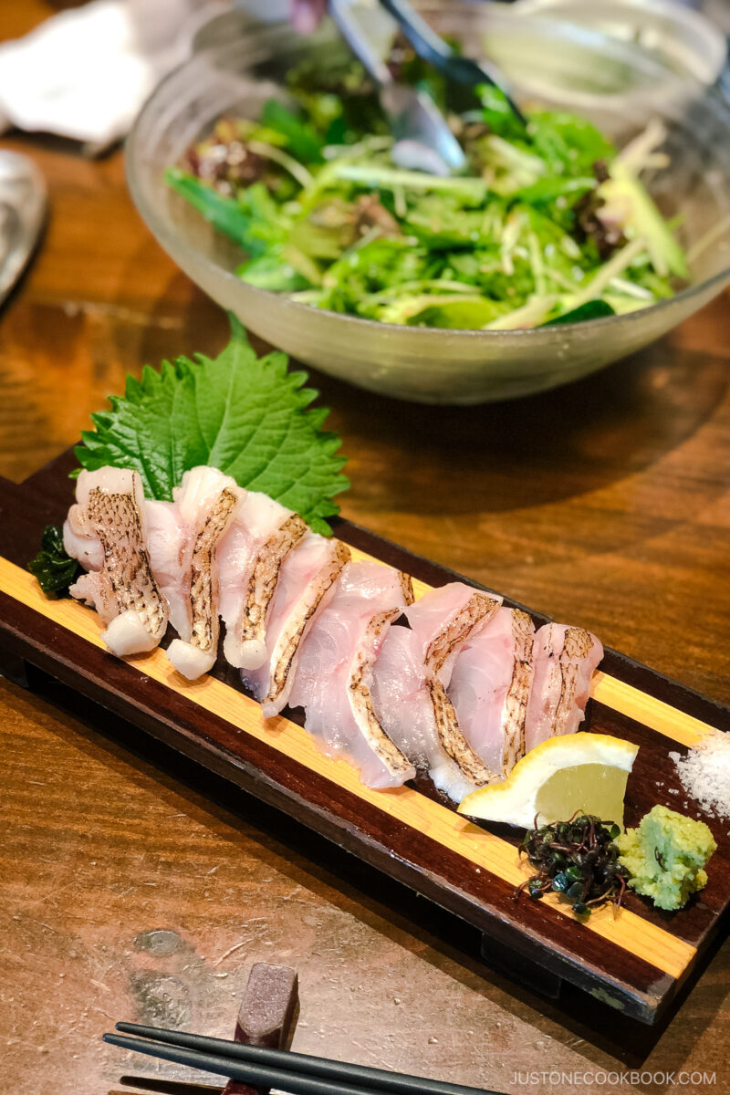 seared slices of fish on a black plate