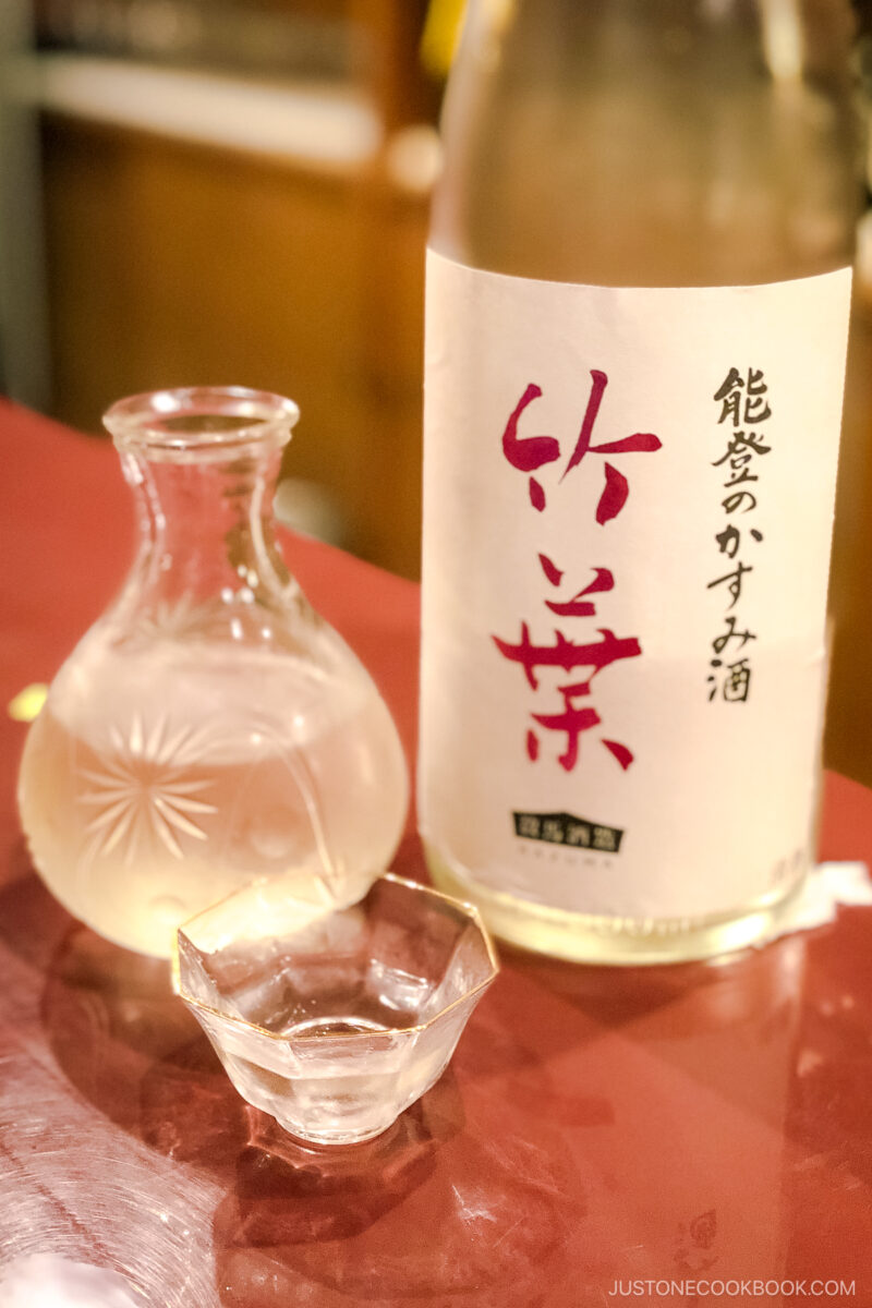 a bottle of sake next to glass and cup