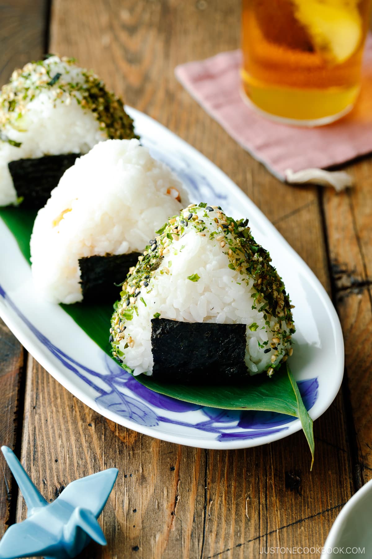 An oval plate containing 3 pieces of Onigiri (Japanese Rice Balls) placed on a bamboo leaf.