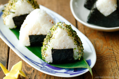 An oval plate containing 3 pieces of Onigiri (Japanese Rice Balls) placed on a bamboo leaf.