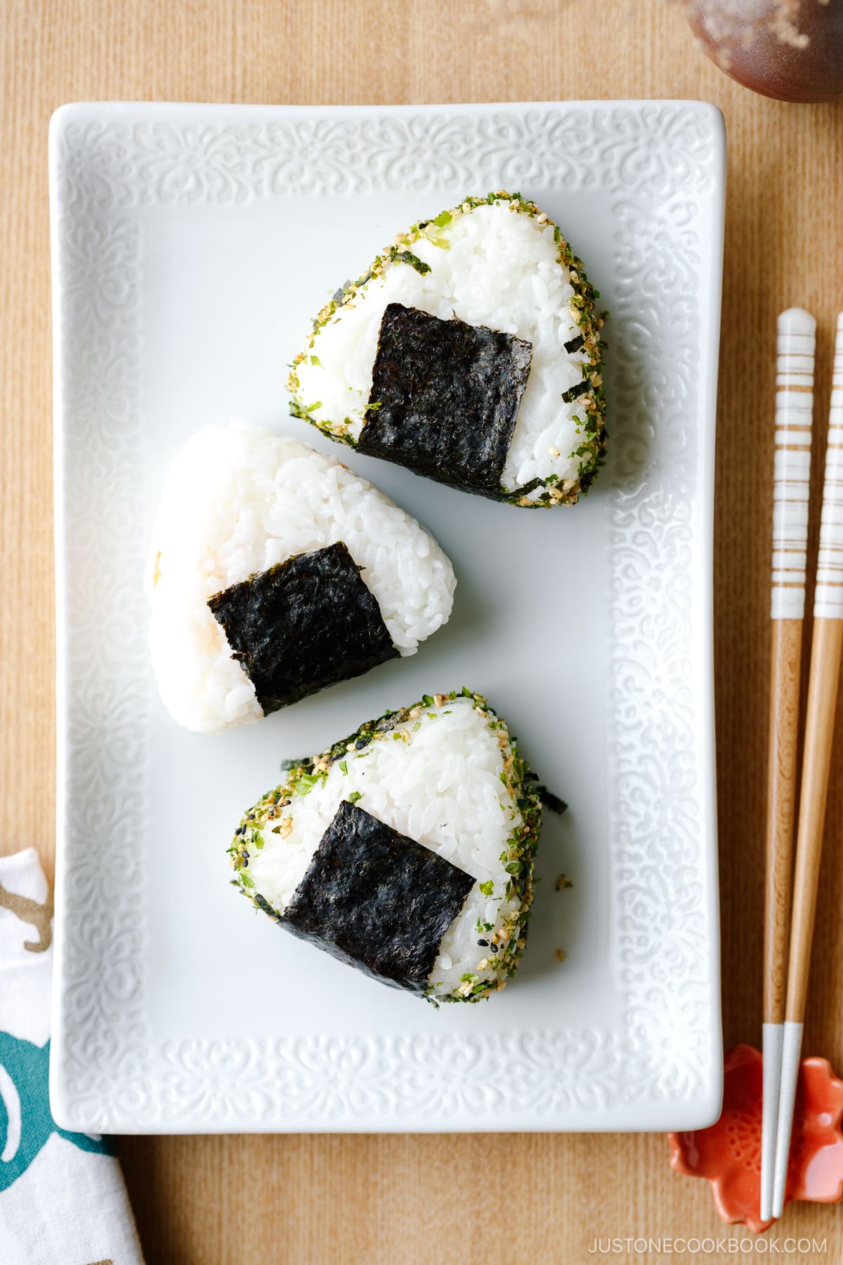 A rectangular white plate containing 3 onigiri (Japanese rice balls).