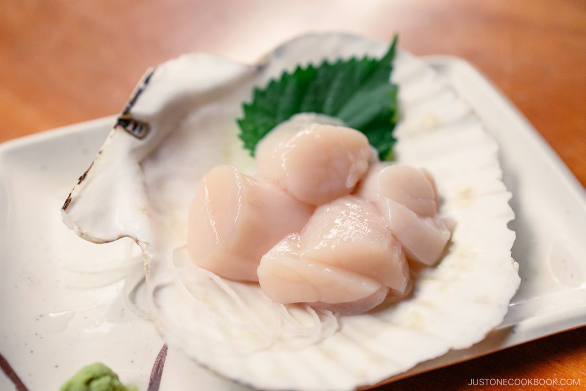 Raw scallops served with shiso in the scallop shell