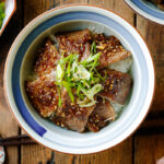 A Japanese donburi bowl containing Yakiniku Don, where pan-grilled well-marbled beef is coated with Japanese BBQ sauce and served over a bed of steamed rice.