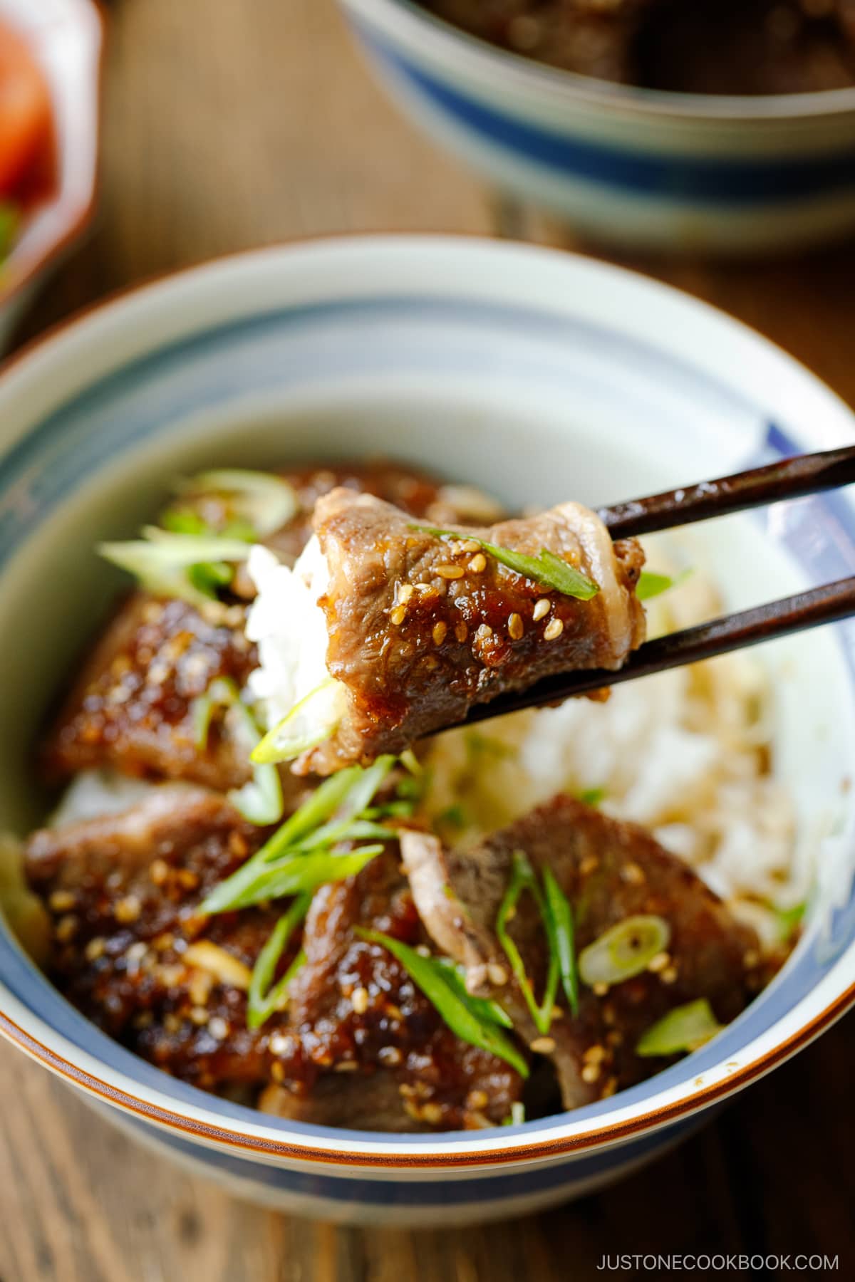 A Japanese donburi bowl containing Yakiniku Don, where pan-grilled well-marbled beef is coated with Japanese BBQ sauce and served over a bed of steamed rice.