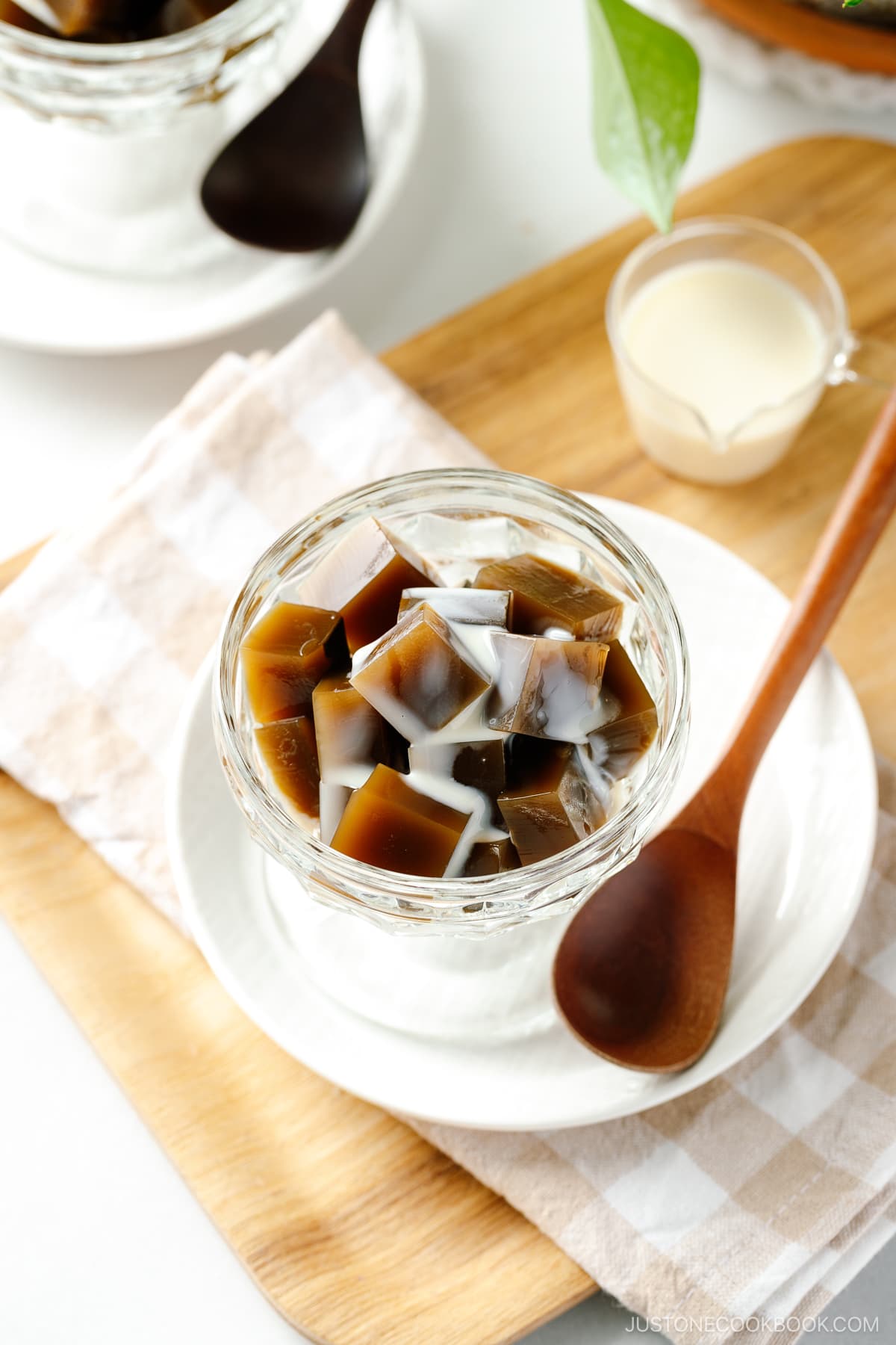 A glass bowl containing cubed Hojicha Jelly drizzled with sweetened condensed milk.