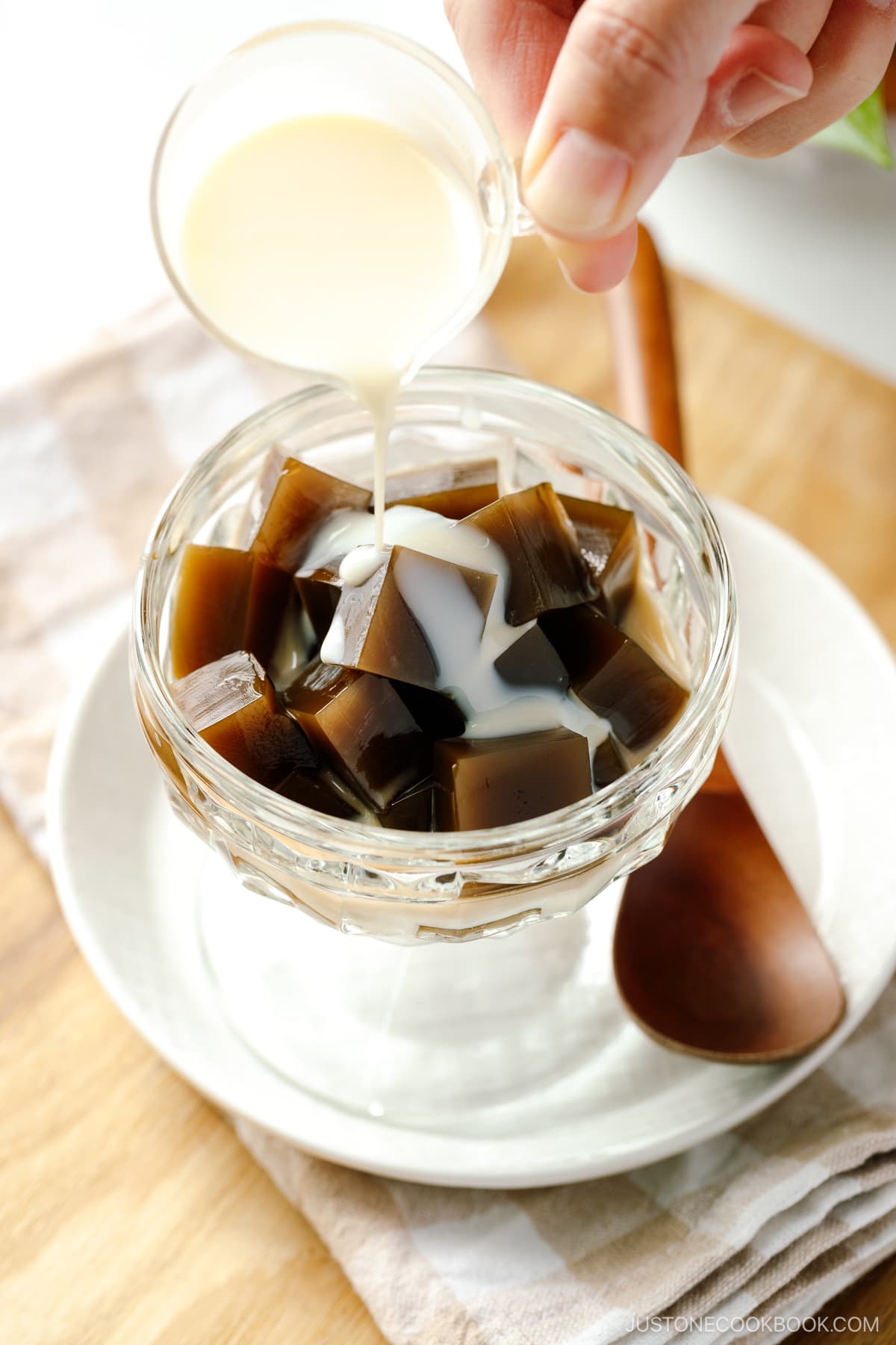 A glass bowl containing cubed Hojicha Jelly drizzled with sweetened condensed milk.