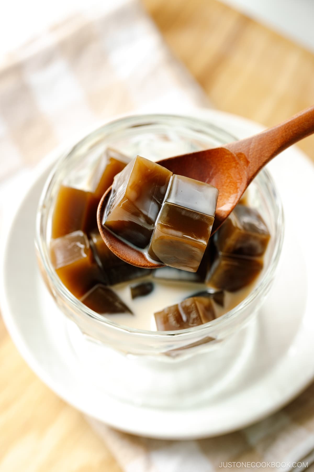 A glass bowl containing cubed Hojicha Jelly drizzled with sweetened condensed milk.